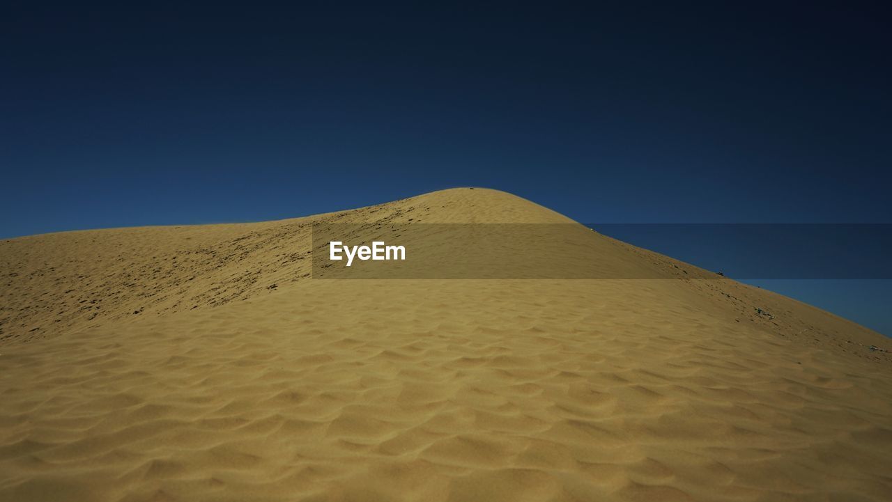 SAND DUNES AGAINST CLEAR SKY