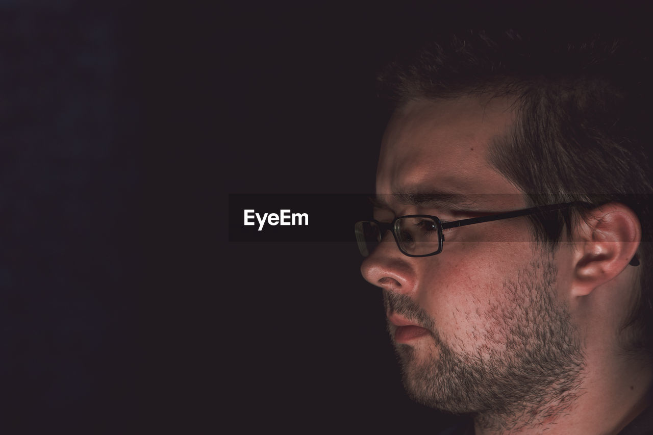 Close-up of serious man looking away against black background