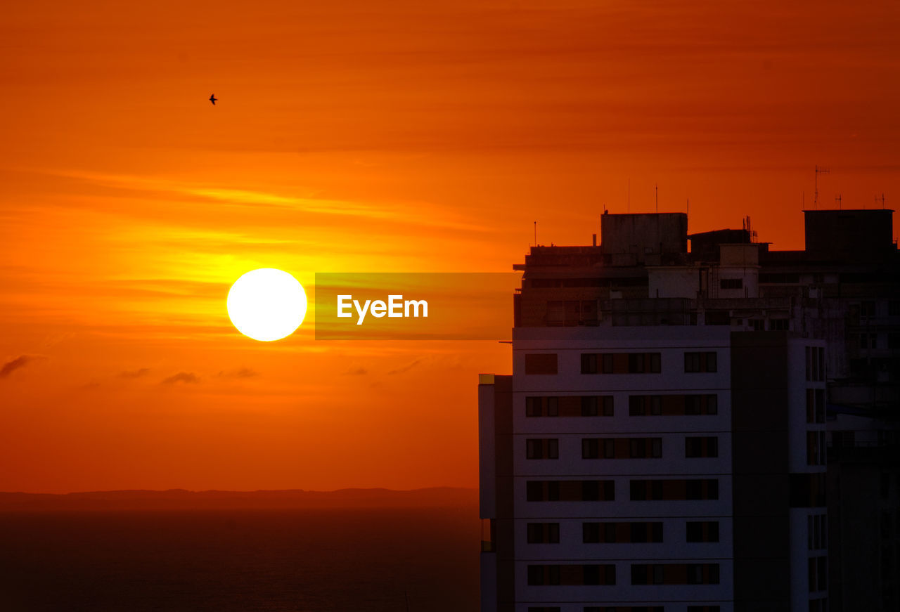 Silhouette buildings against sunrise