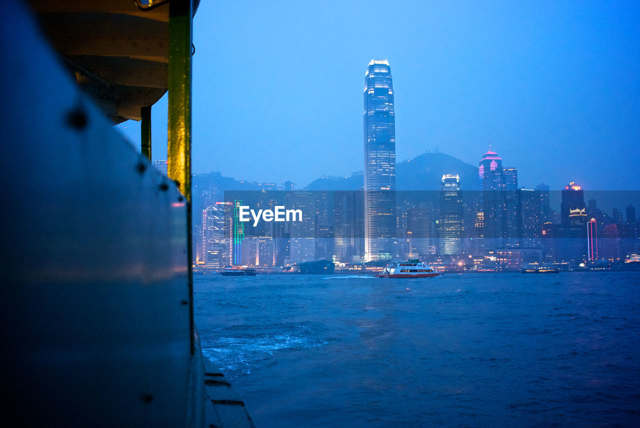 Buildings at victoria harbour in city at dusk