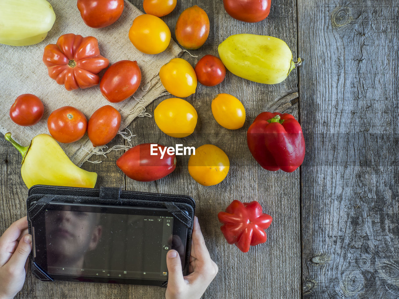 Reflection of man on digital tablet by fresh vegetables on table