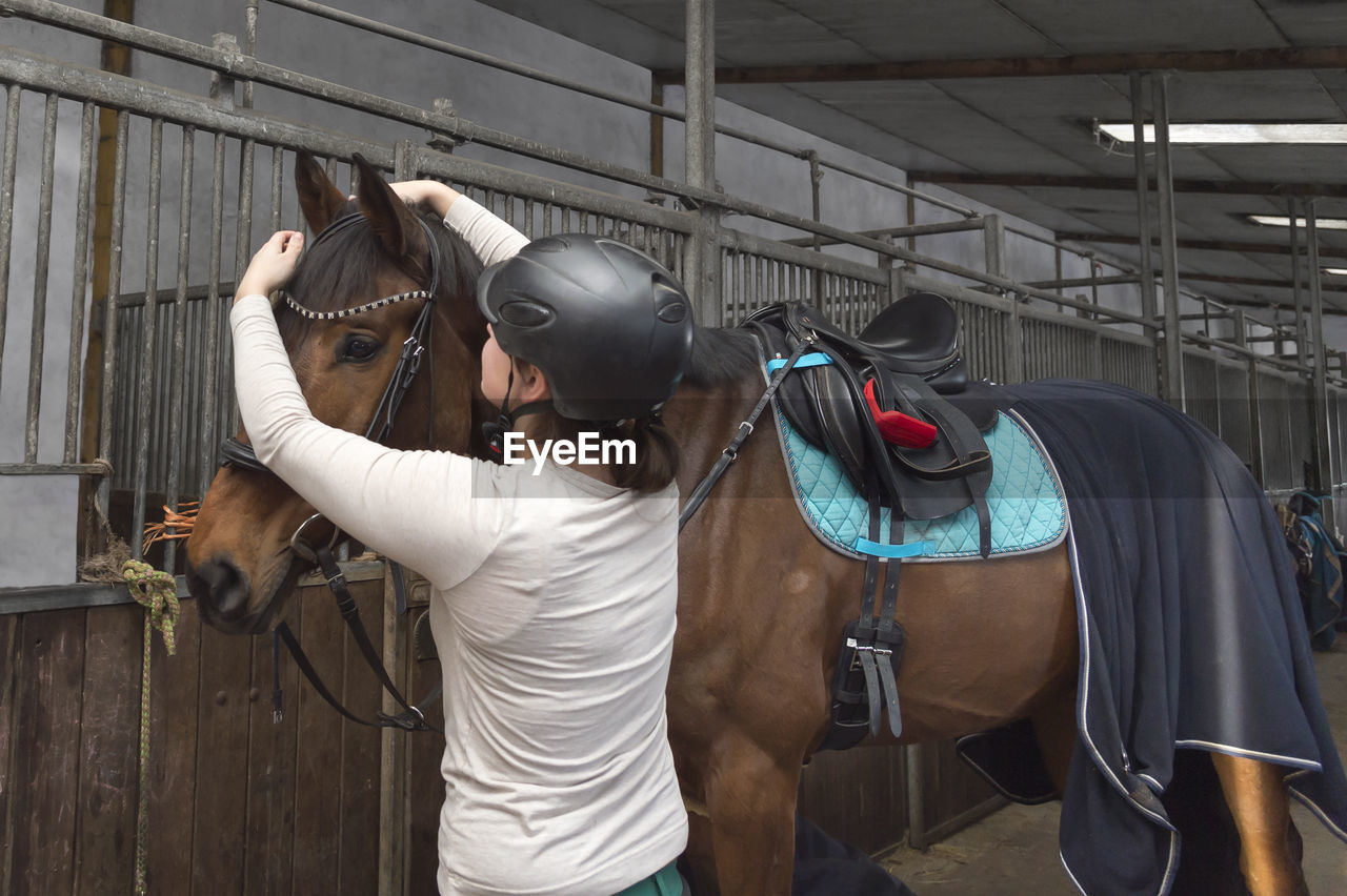 Rear view of woman with horse standing stable