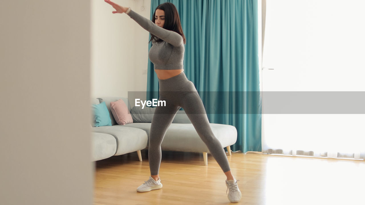 low section of woman doing yoga on bed at home