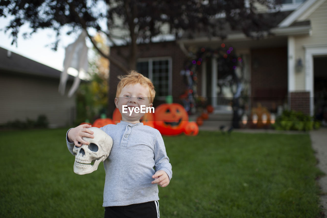 Toddler boy excited about holding skull in front of halloween decor