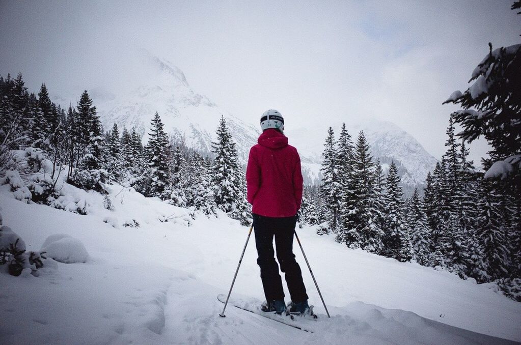 WOMAN WALKING ON SNOW COVERED MOUNTAIN