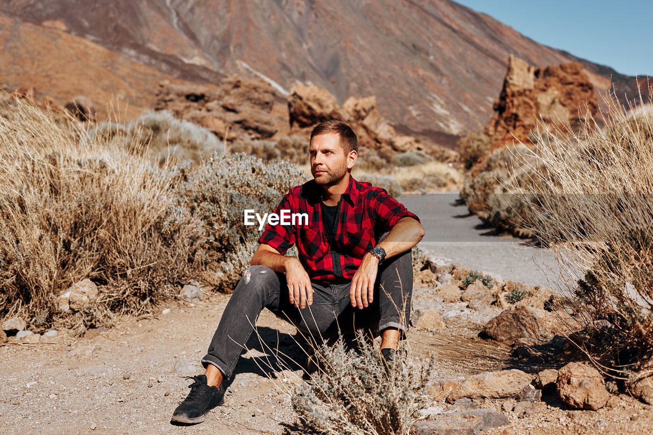 Man looking away while sitting on land