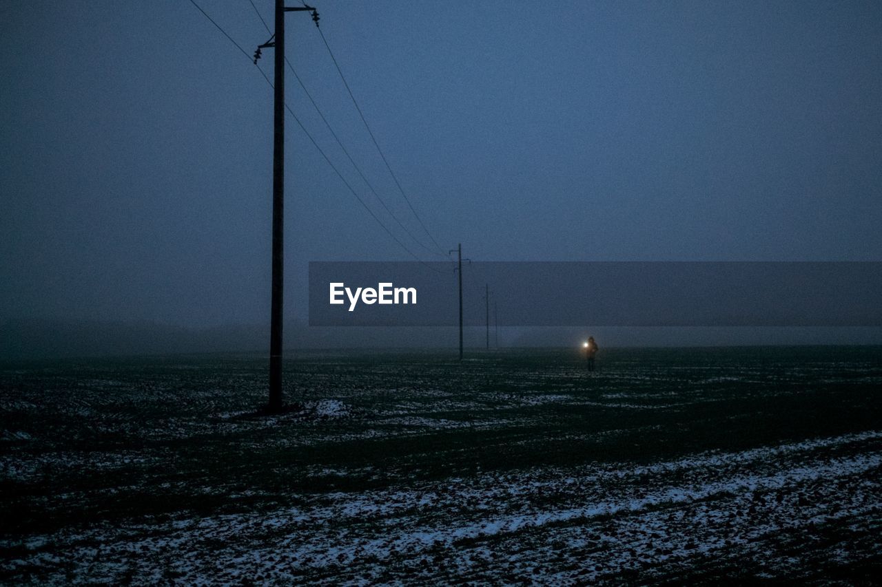 Electricity pylon on field against sky during winter