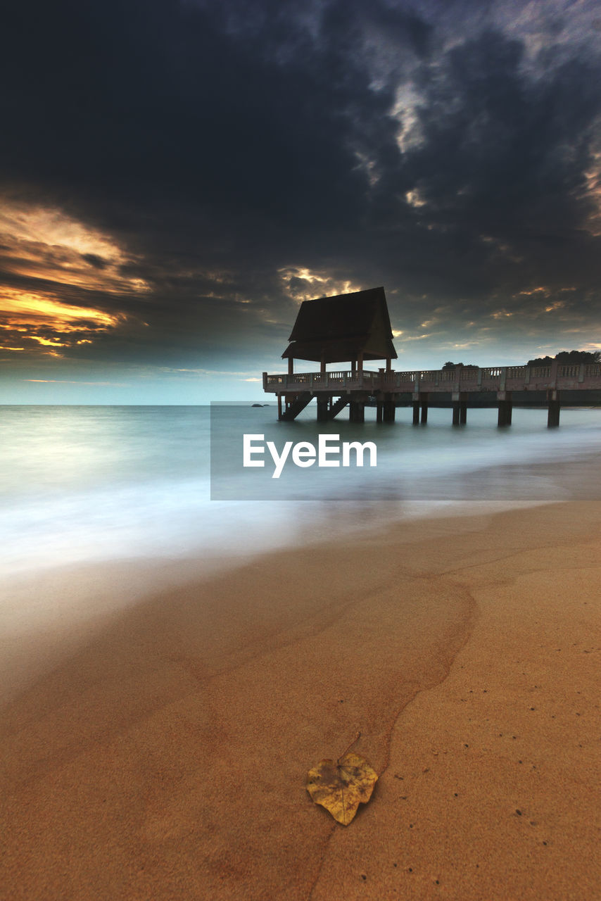 Lifeguard hut on beach against sky during sunset