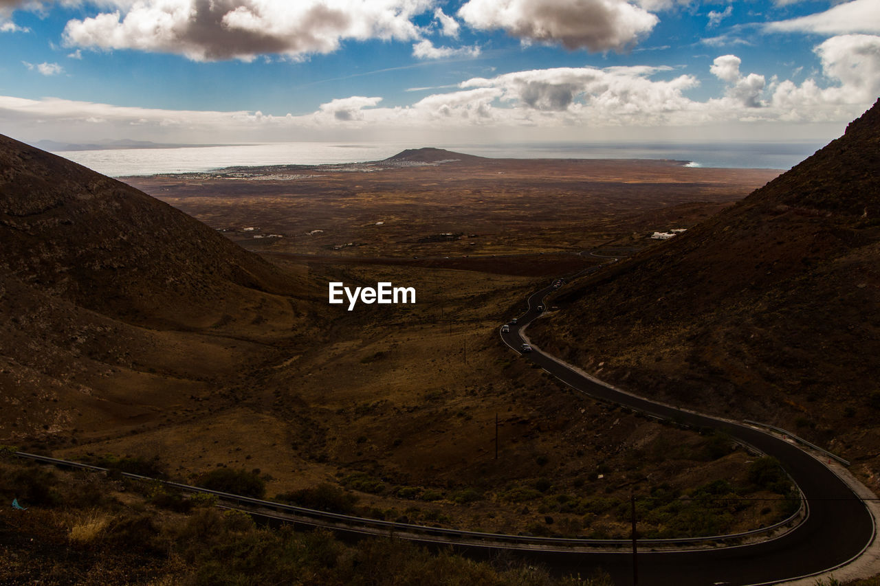 Scenic view of road by mountains against sky