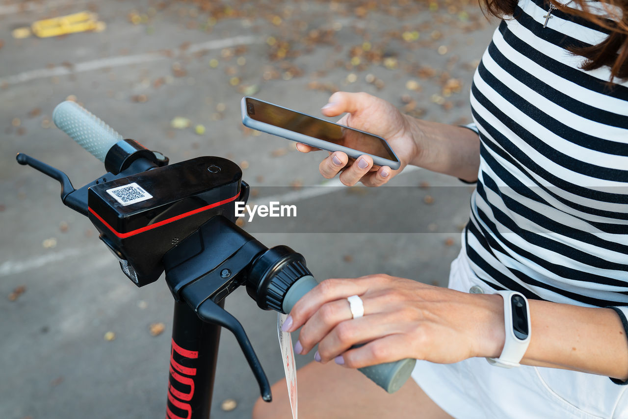 A girl rents an electric scooter with an application on her phone.