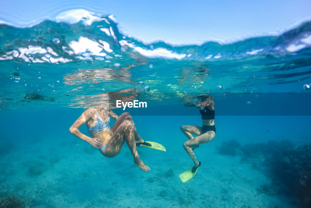 Females in swimsuit swimming under sea