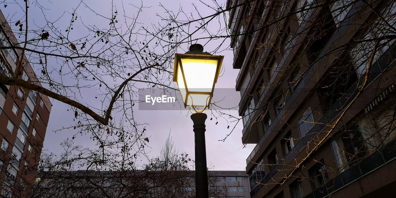 LOW ANGLE VIEW OF ILLUMINATED STREET LIGHT BY BUILDING