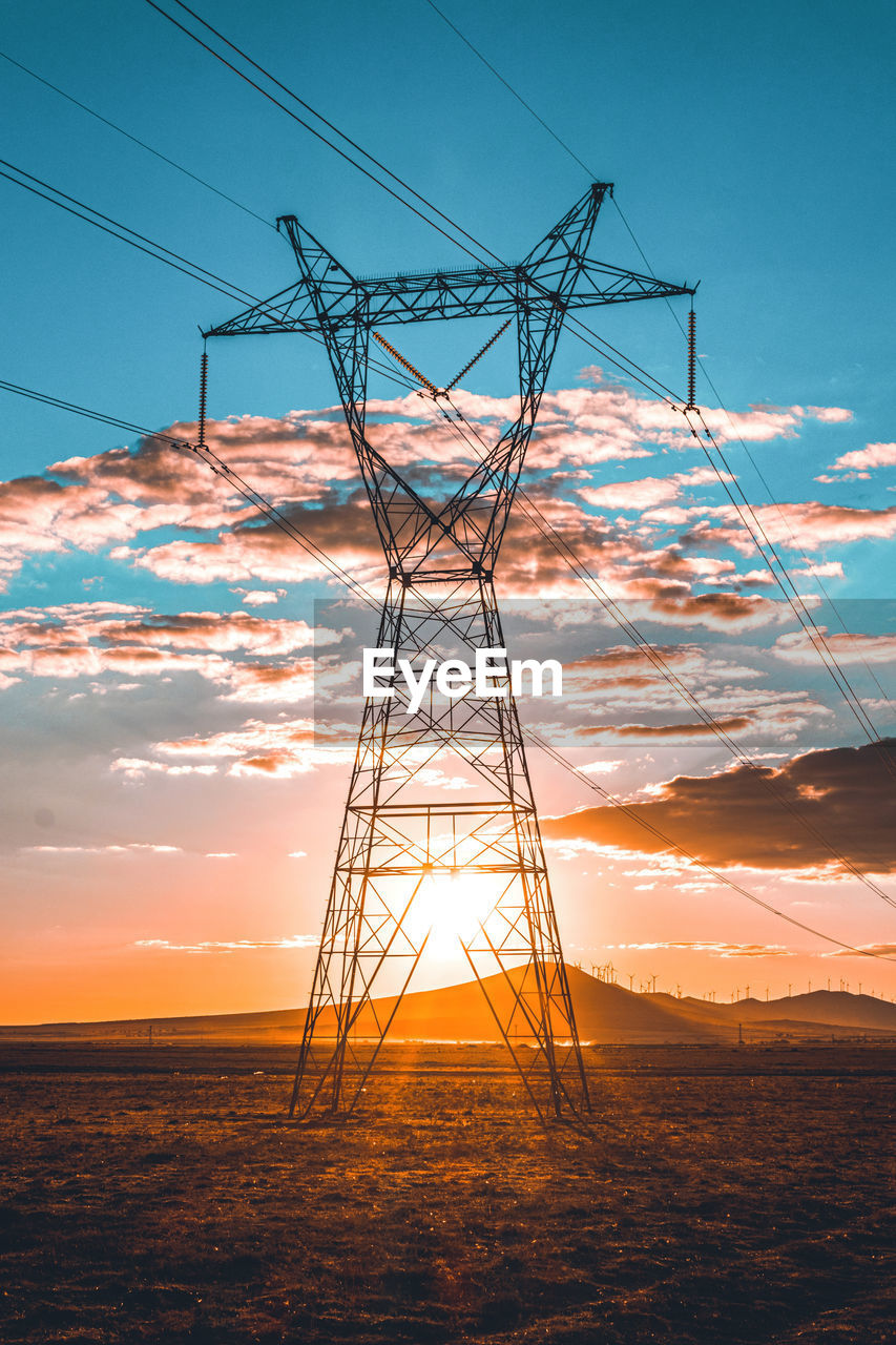 Low angle view of electricity pylon against sky during sunset