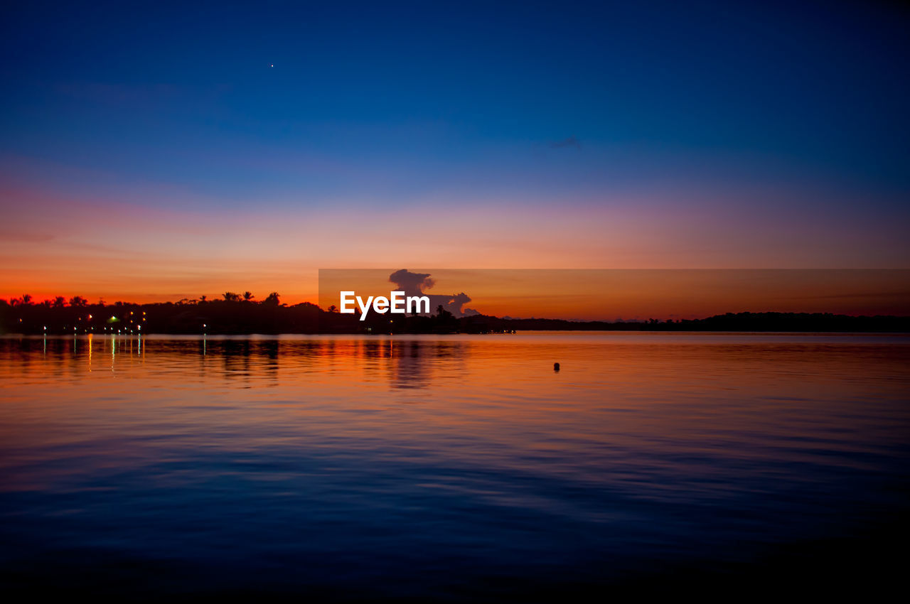 Scenic view of lake against sky at sunset