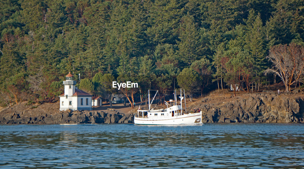 Scenic view of sea against trees with yacht