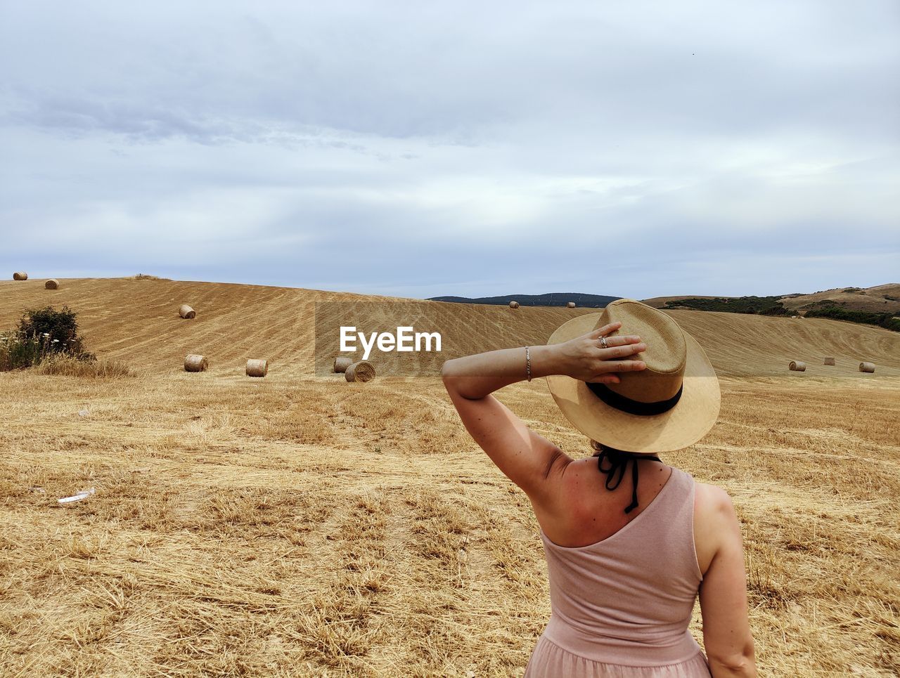 Rear view of woman standing on field against sky