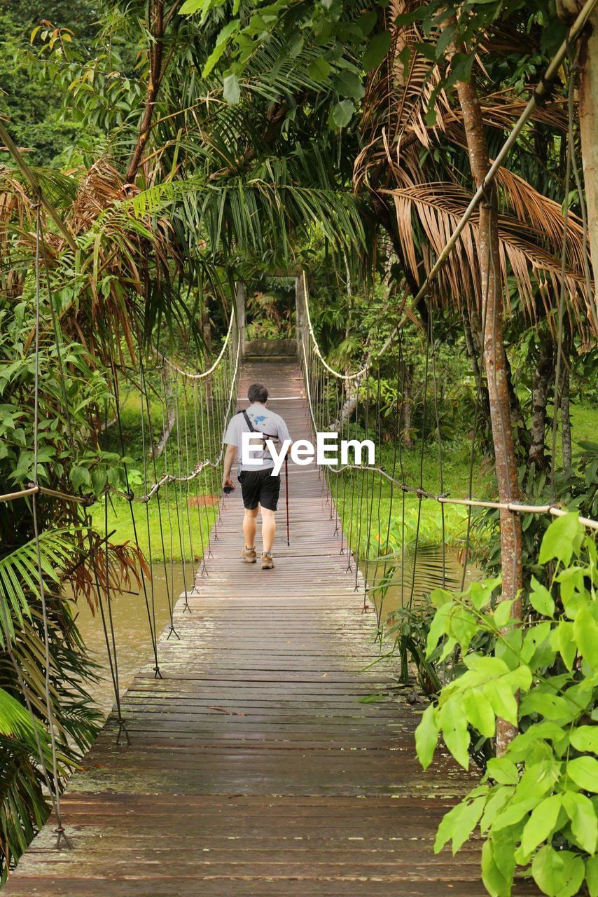 Rear view of man walking on footbridge