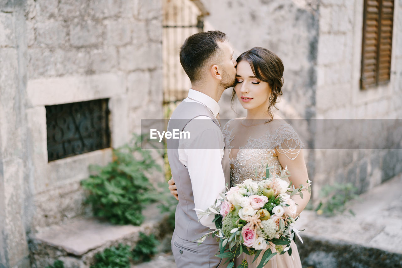 side view of bride holding bouquet while standing outdoors