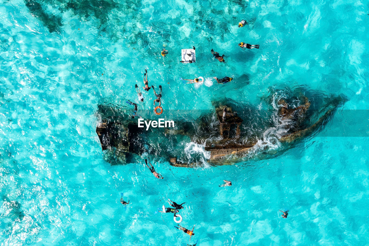 People snorkelling around the ship wreck near cancun in the caribbean sea.