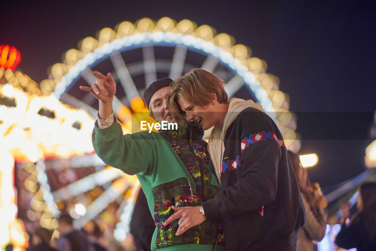 Drunk men standing at amusement park during night