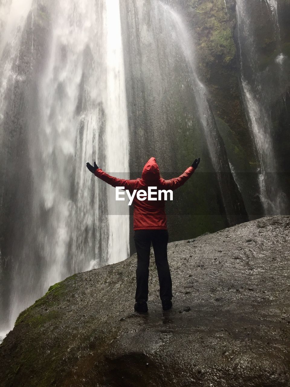 rear view of man standing on rock against waterfall