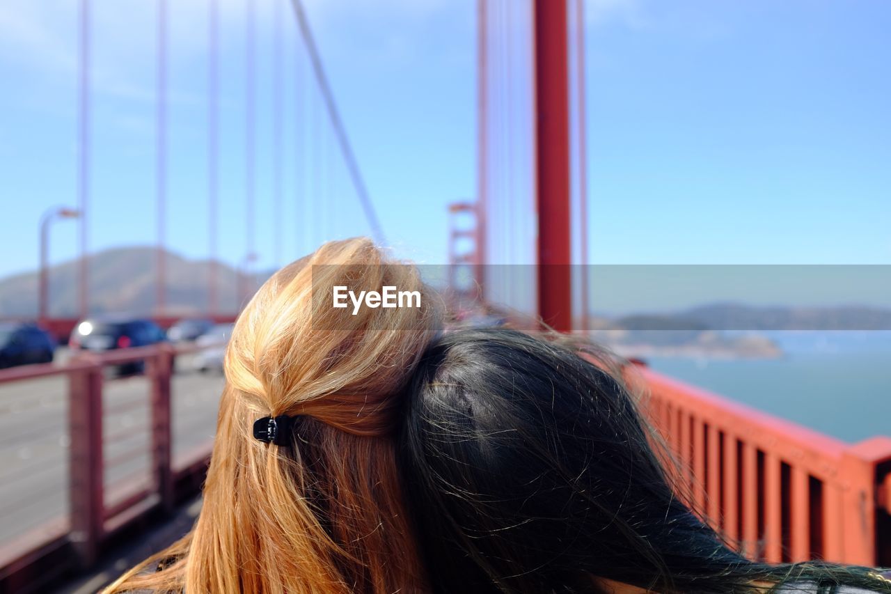 Two women on suspension bridge over sea