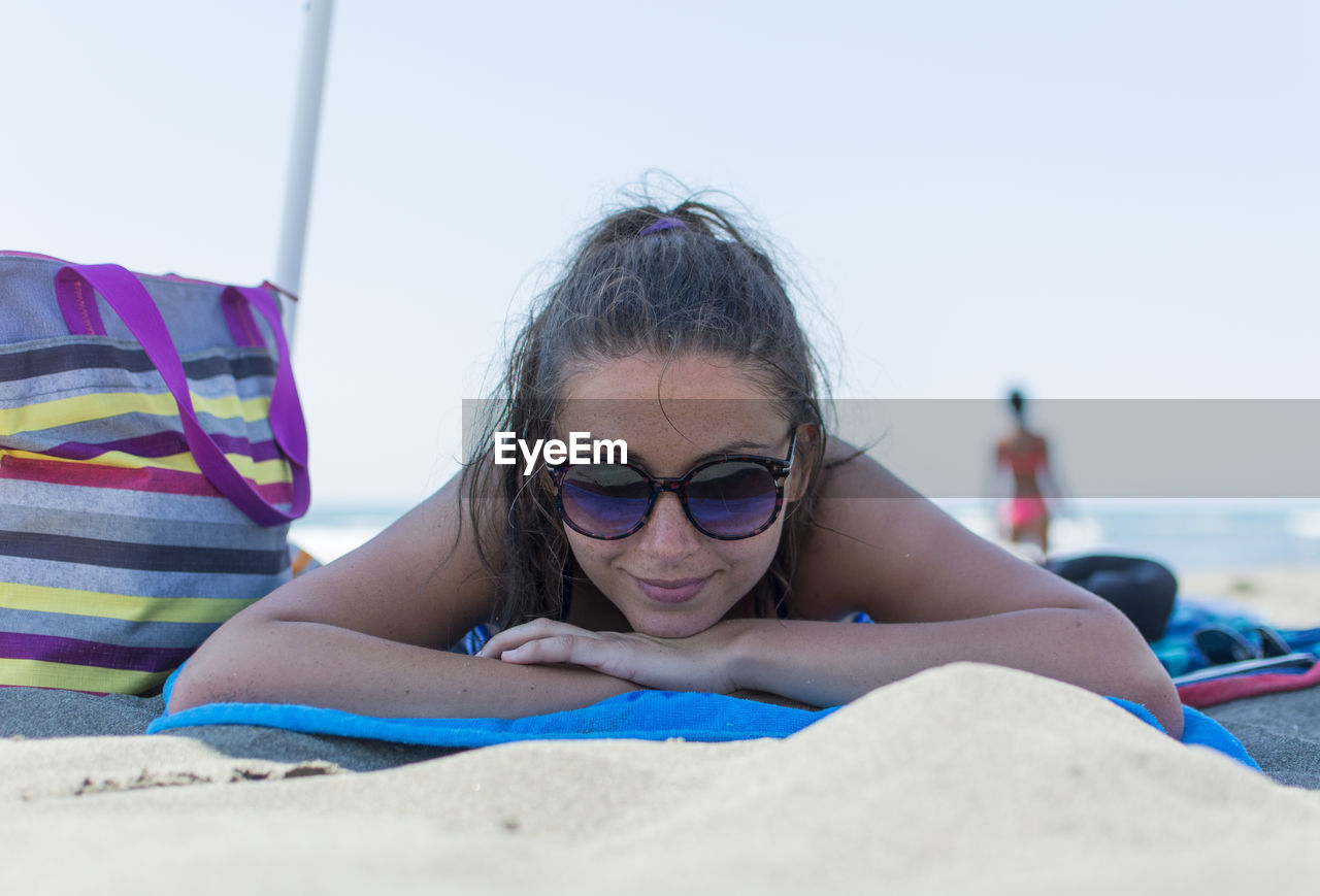 Portrait of woman in sunglasses lying on sand