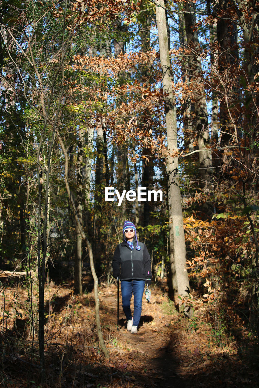 Woman walking on land amidst trees in forest