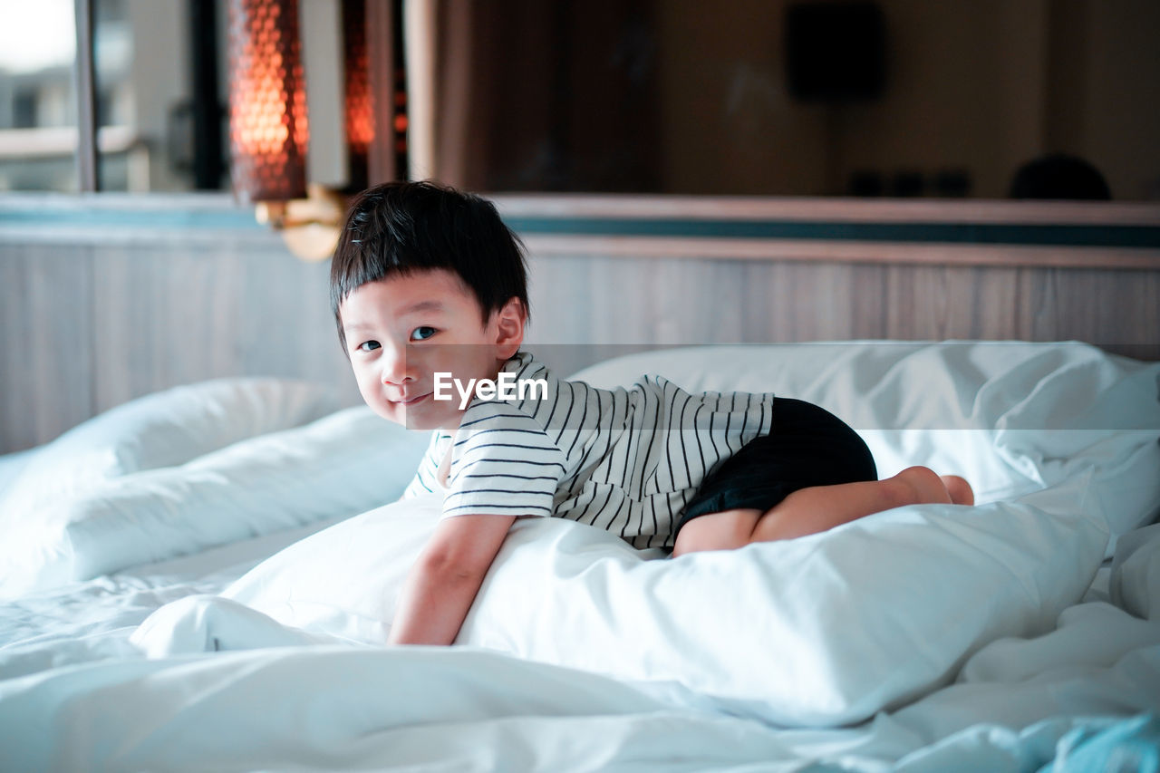 Baby boy kneeling on bed at home