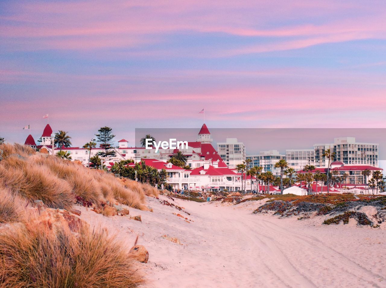 Buildings at beach against sky during sunset