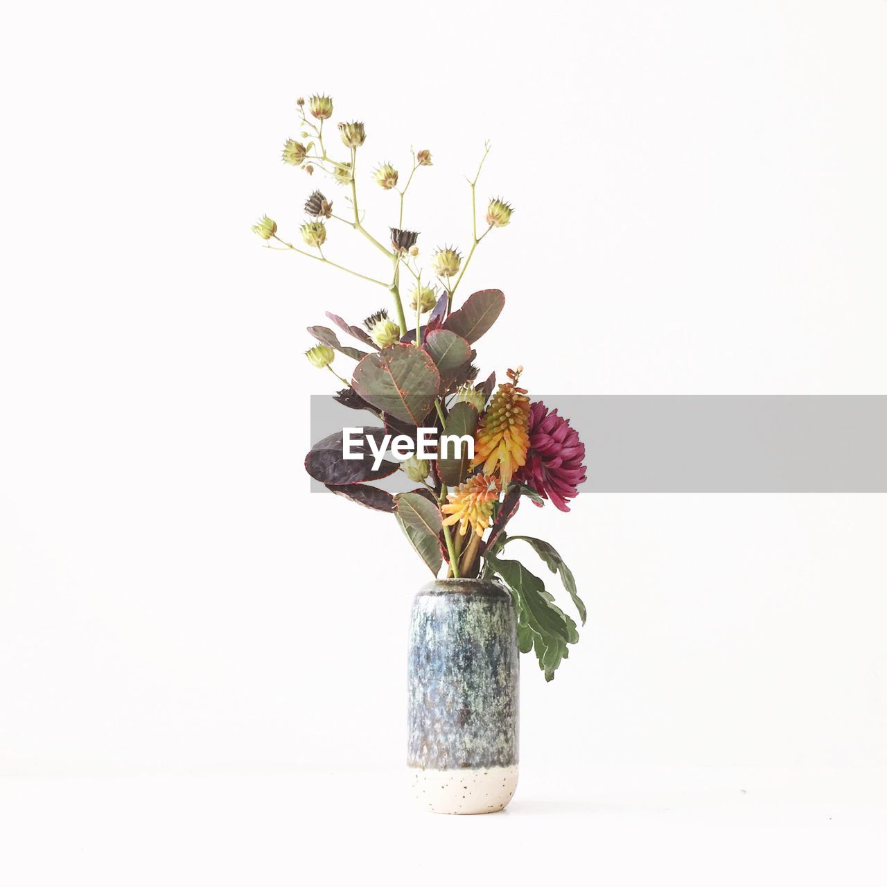 Artificial flowers in vase against white background