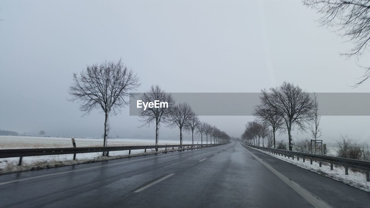 ROAD BY BARE TREES AGAINST CLEAR SKY