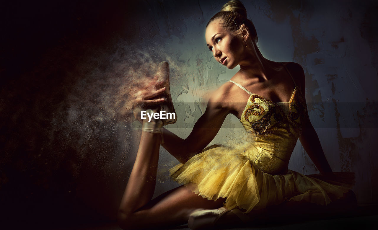 Digital composite image of ballet dancer stretching by wall