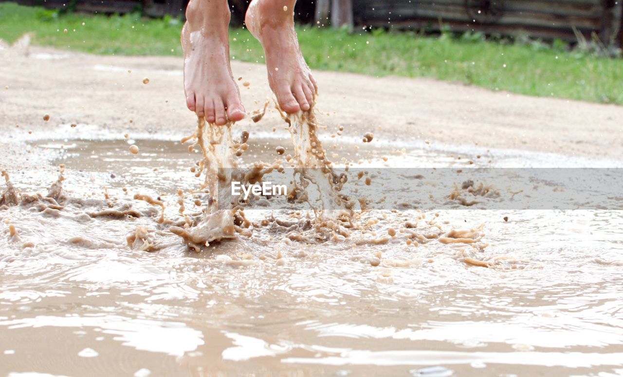 Low section of person splashing water in puddle