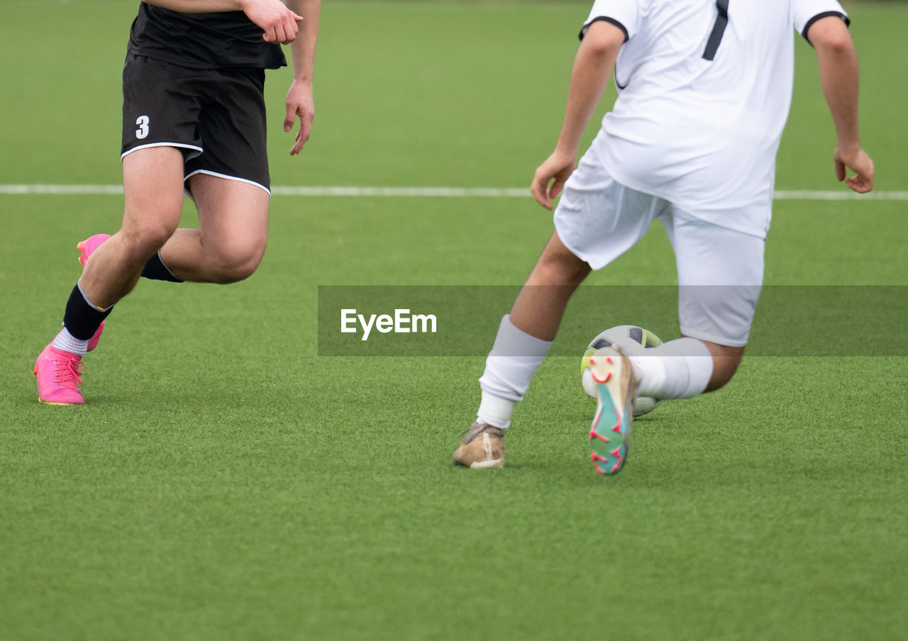 low section of man playing soccer at park