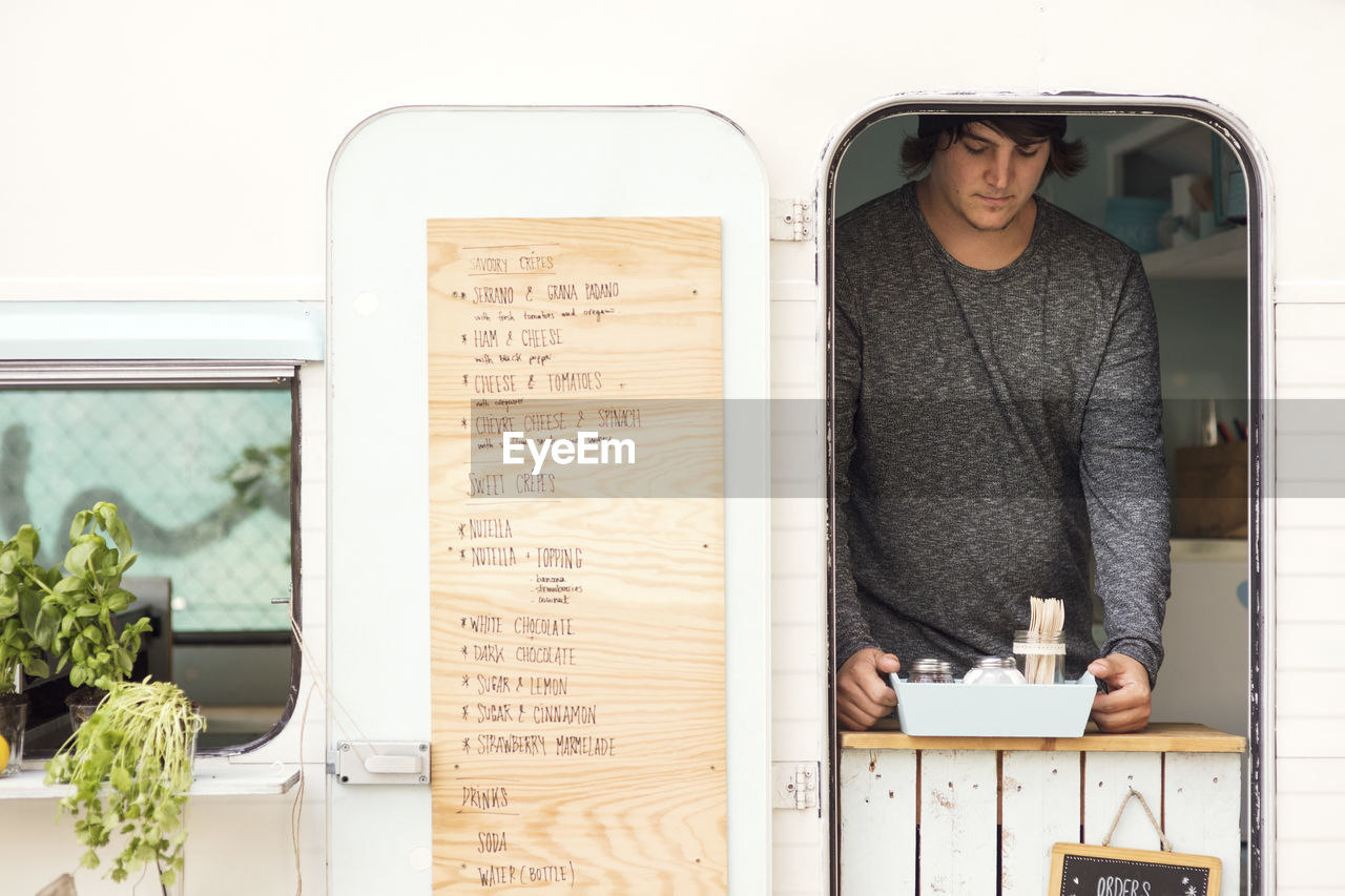 Male owner placing container at food truck window