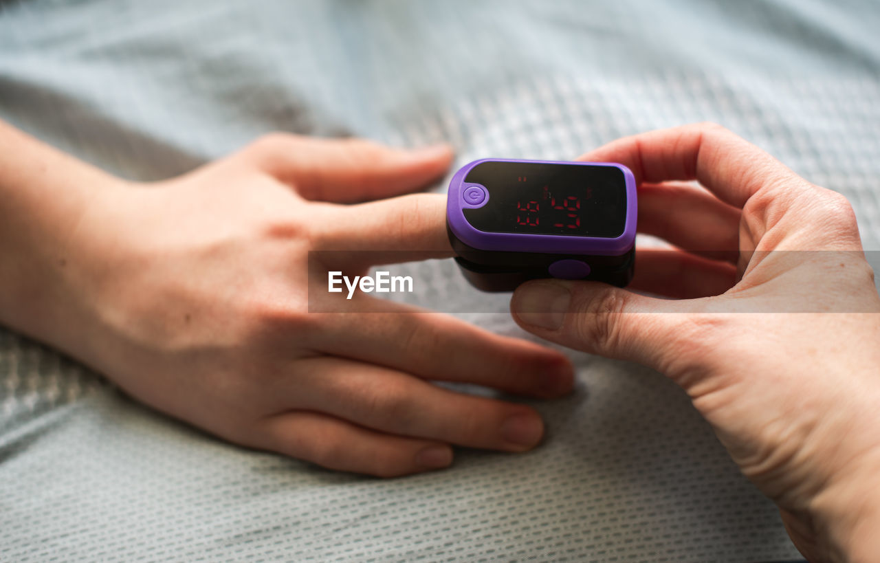 Close up of a hand putting a pulse oximeter on someone's finger.