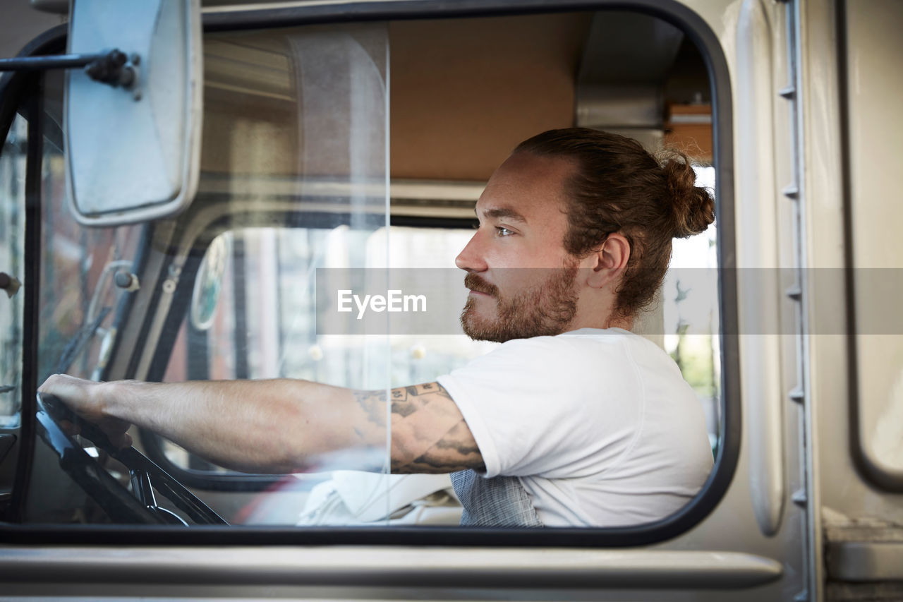 Side view of young man driving food truck in city