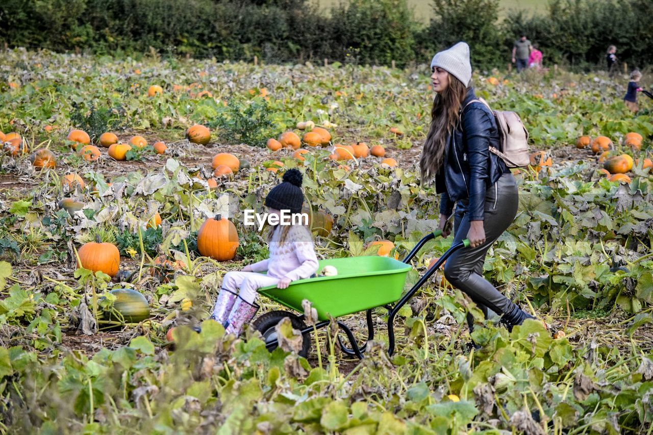 REAR VIEW OF WOMEN STANDING BY PUMPKIN