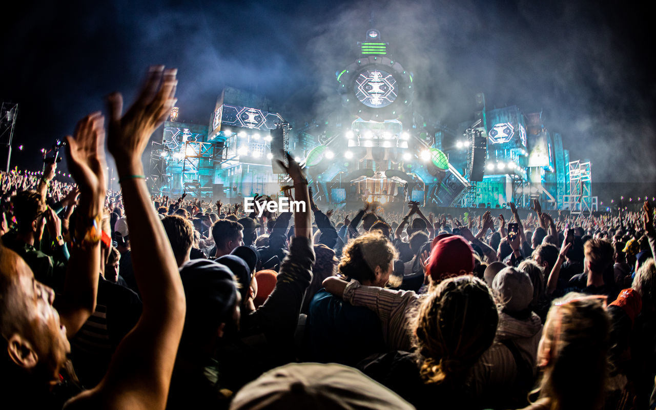 REAR VIEW OF PEOPLE ENJOYING MUSIC FESTIVAL