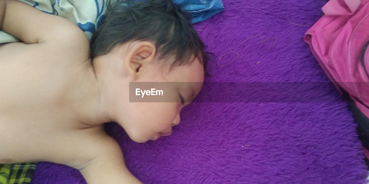 HIGH ANGLE VIEW OF BABY BOY SLEEPING ON BED