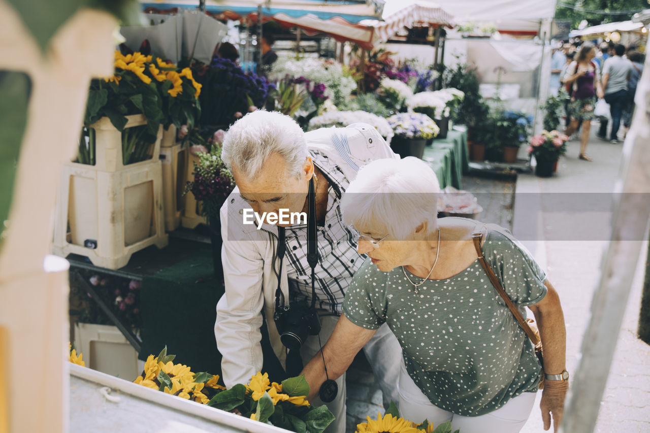 Senior couple shopping for flowers at market in city during vacation