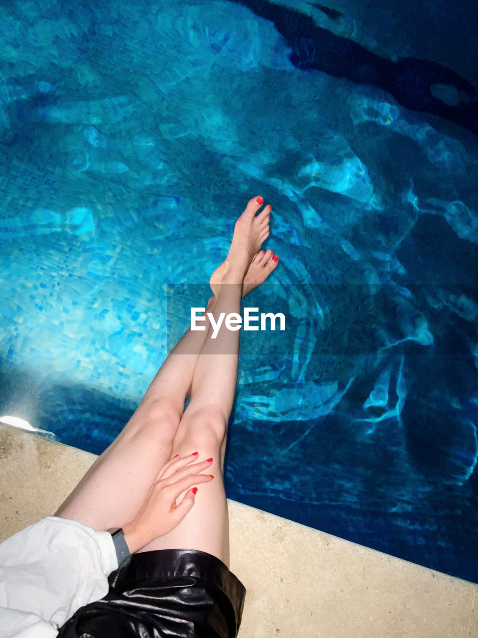 Low section of woman relaxing in swimming pool