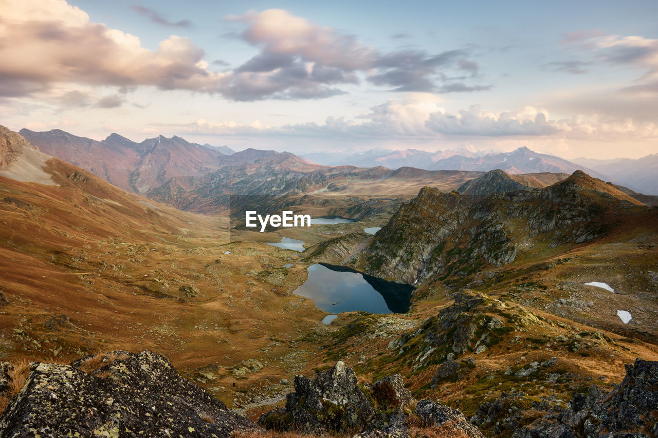 Mountains at sunset, gold alpine field, lakes and mountain ranges, travel and mountain life