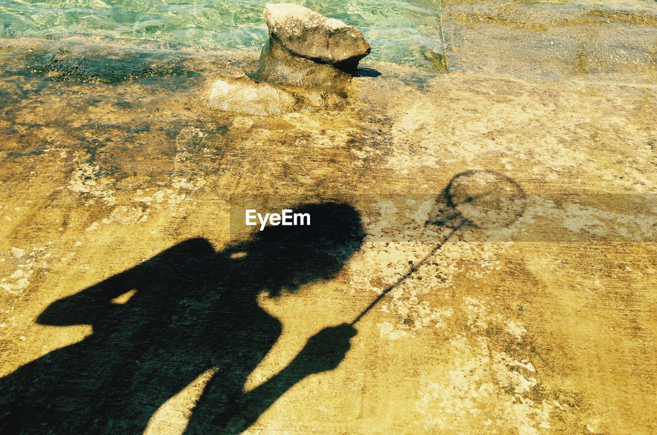 Shadow of woman with fishing net at beach