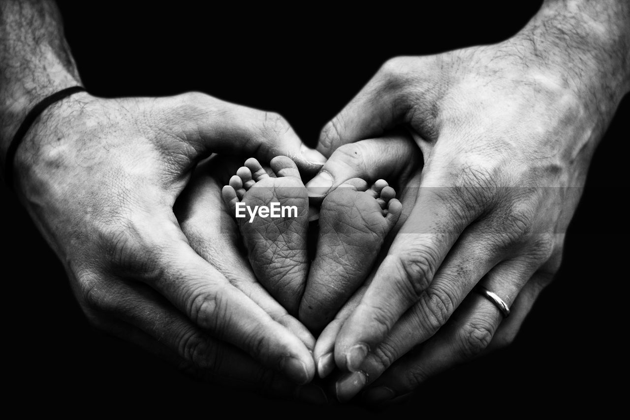 Close-up of parents hands holding baby