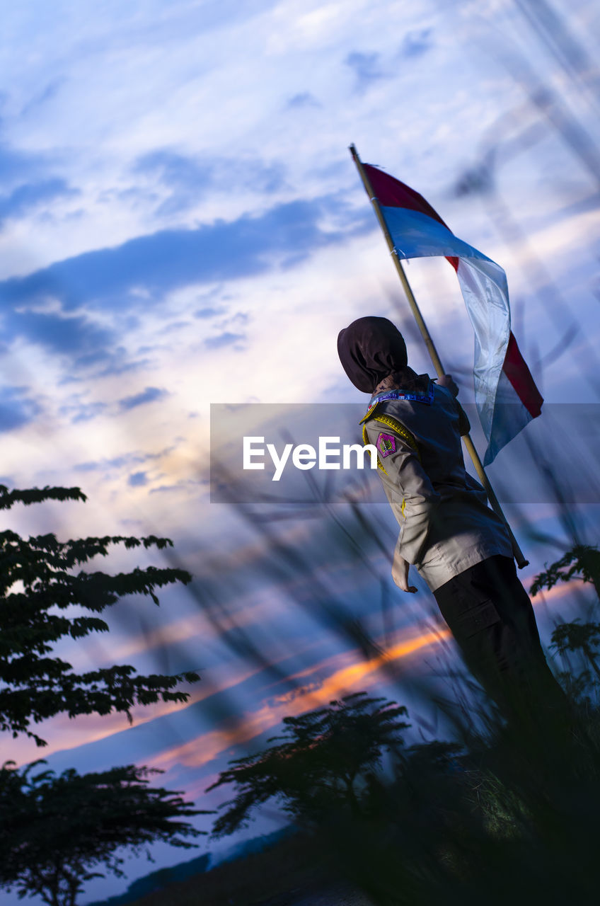 LOW ANGLE VIEW OF FLAGS AGAINST SKY AT SUNSET