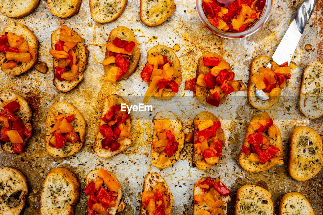 Bruschetta toasts on baking sheet  and spread with gourmet oil and pepper topping