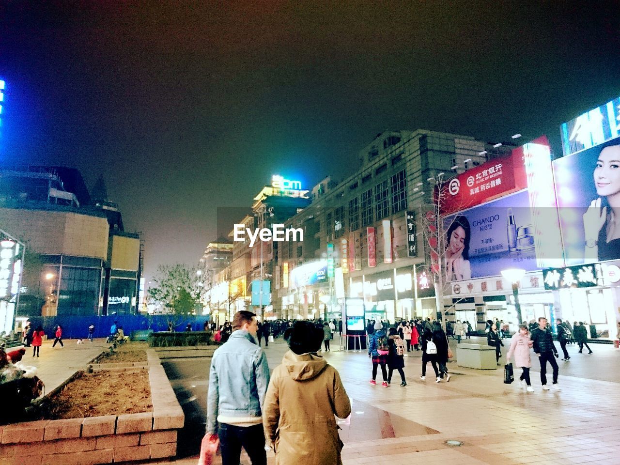 PEOPLE WALKING ON ILLUMINATED STREET AT NIGHT