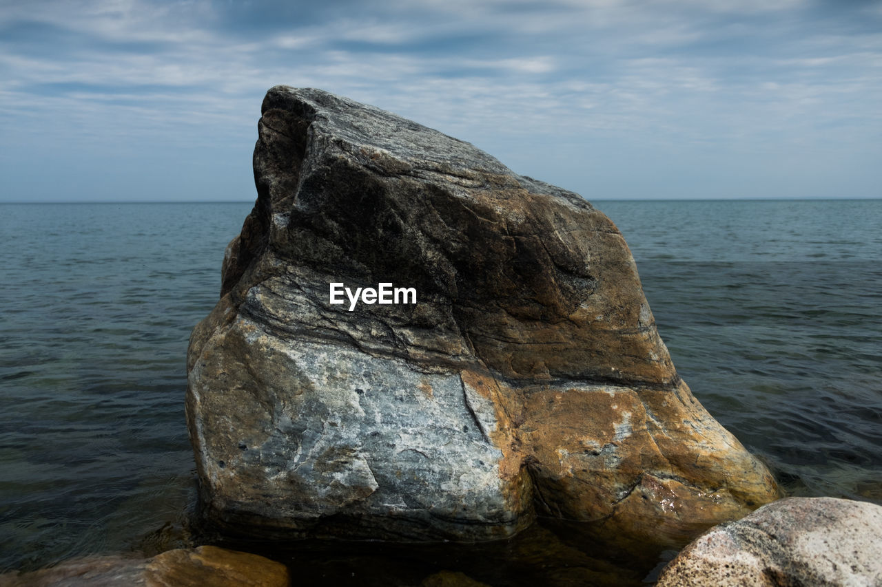 Rock formation on sea shore against sky